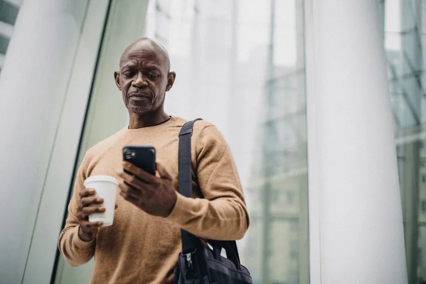 Man in front of city building looking at cell phone