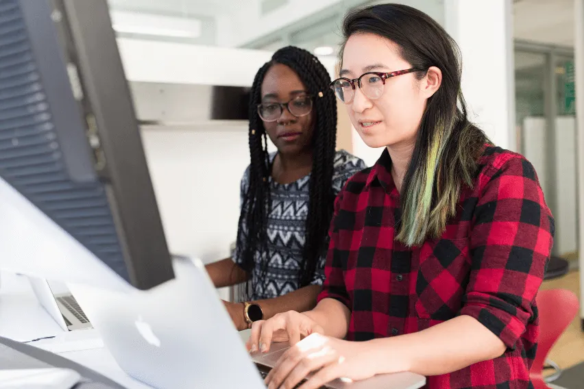 Two women are looking at a computer screen together