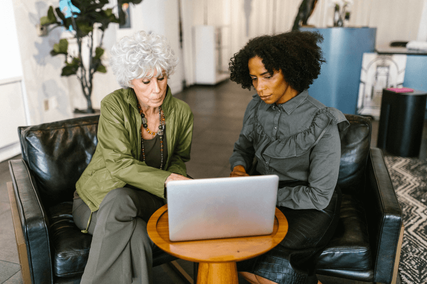 Two professional women work at laptop