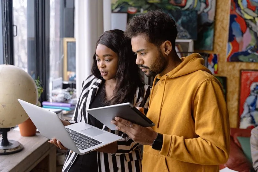 coworkers in office standing and looking at laptop together